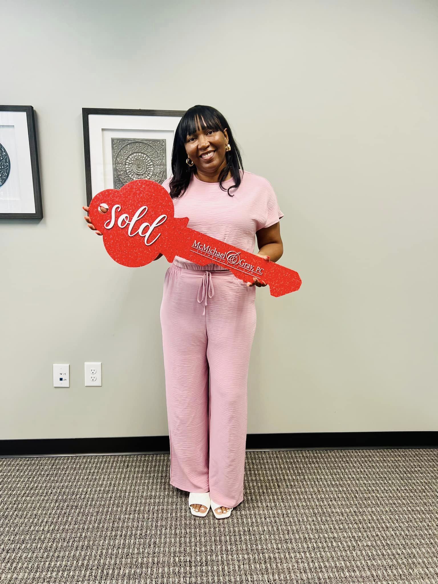 Happy customer holding a "Sold" sign after buying a home with the help of a professional realtor